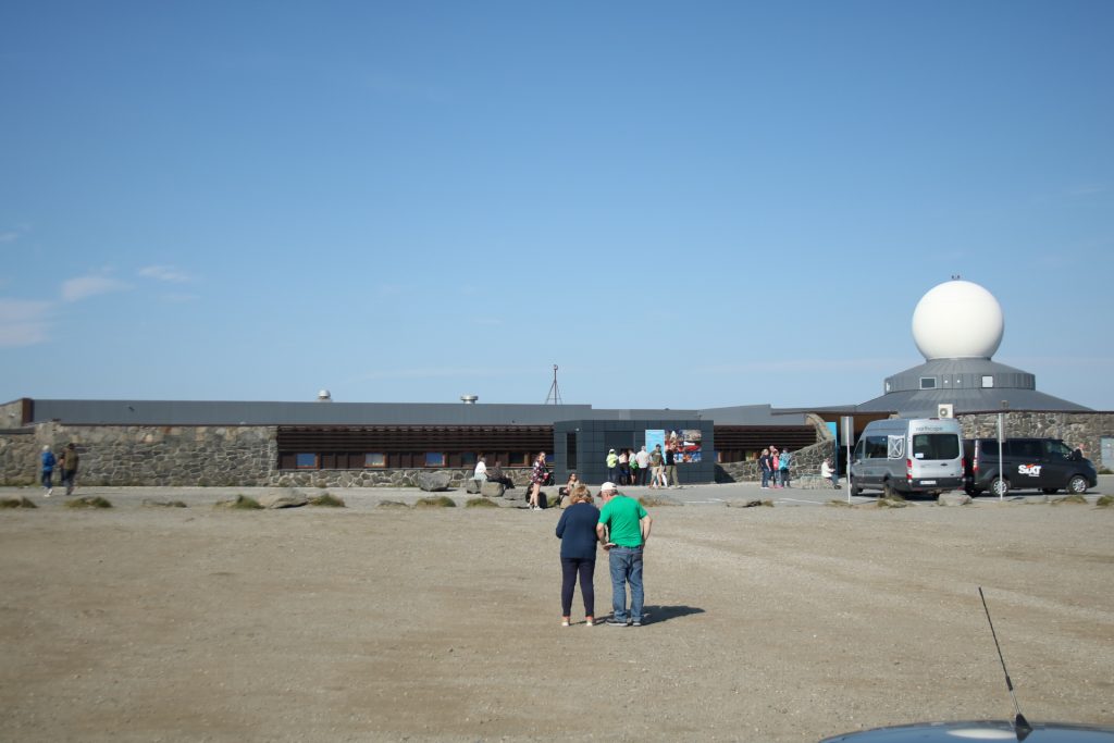 Menachen auf einem sandigen Platz vor einem Gebäude