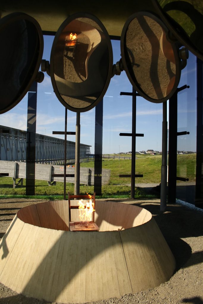 Brennder Stuhl im Betonkreis umgeben von drei Spiegel