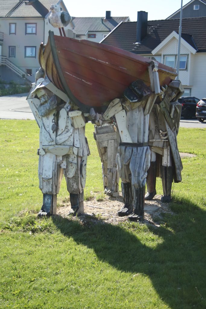 Holzdenkmal: vier Fischer tragen ein Boot