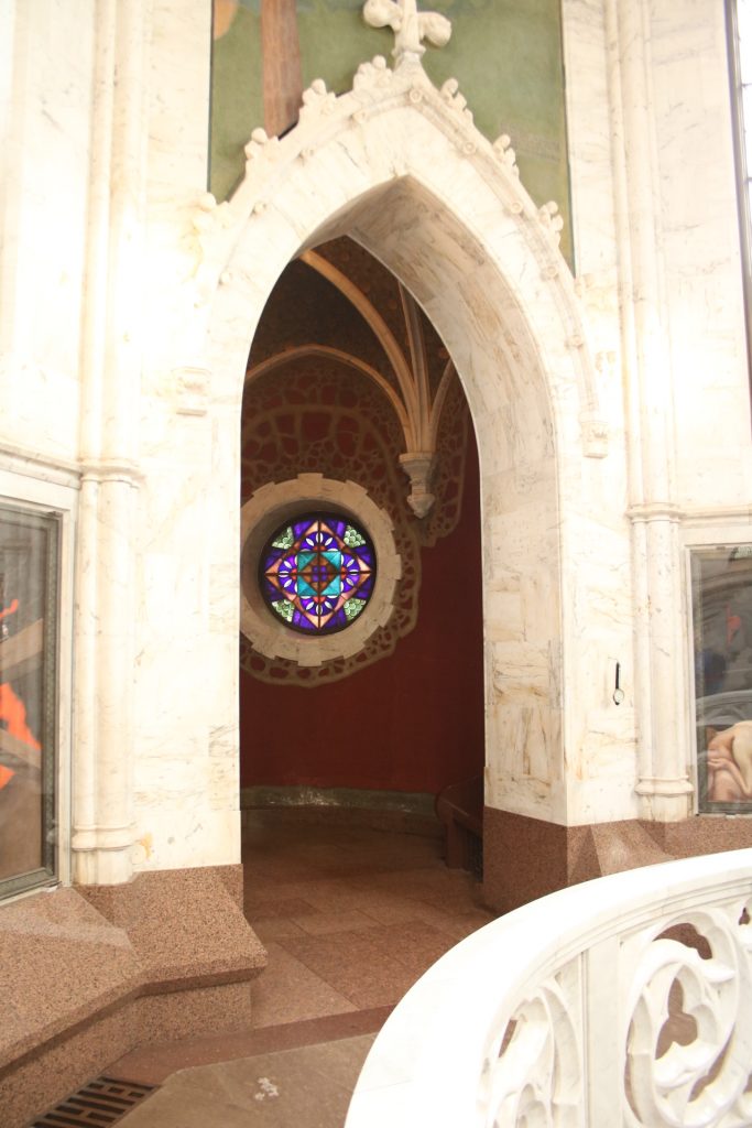 Weißer Marmor Türbogen und roter Raum mit rundem Buntglasfenster