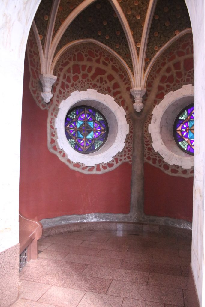 Zwei Buntglasfenster mit weißer Umrandung und rote Wand