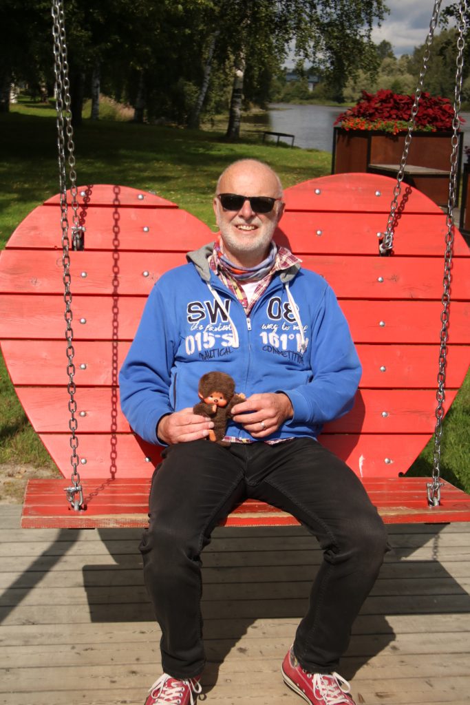 Mann mit blauem Hoody auf roter Herzschaukel