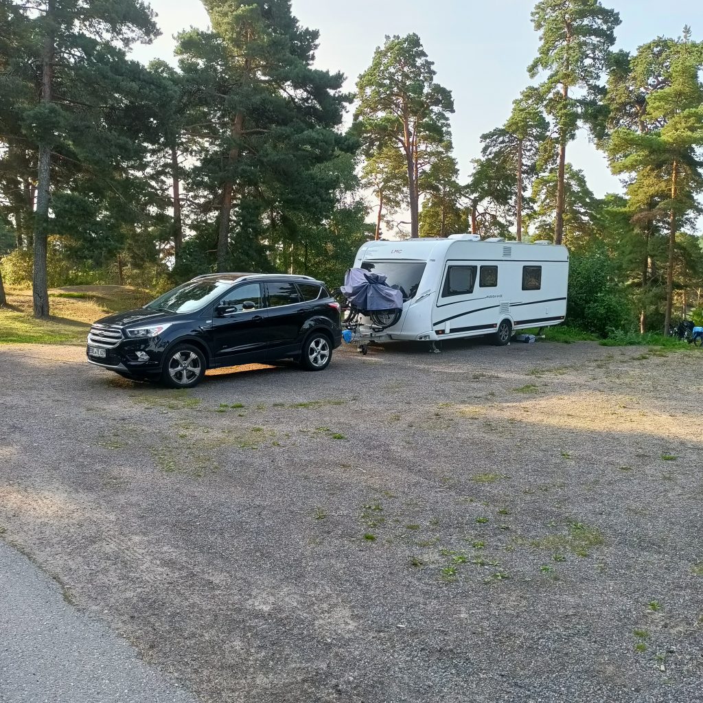 Schwarzes Auto mit Wohnwagen im Wald