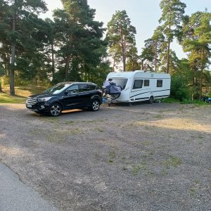 Schwarzes Auto mit Wohnwagen im Wald